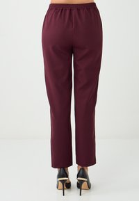Bordeaux elastische taillebroek met een slanke silhoutte en een gladde textuur, gecombineerd met zwarte hoge hakken, die een klassiek ontwerp tonen.