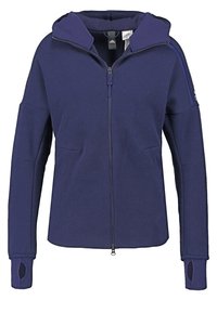 Marineblå zip-up hoodie tillverkad av texturerat tyg, med huva, två frontfickor och tumhål på ärmarna.