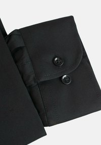 Puño de camisa negra hecho de tejido suave, con dos botones negros y un borde doblado. El puño presenta detalles de costura sutiles.