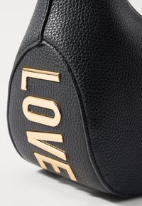 Borsa in pelle nera con texture, caratterizzata da grandi lettere dorate "LOVE" sul lato. Finitura liscia con forma arrotondata e dettagli cuciti.