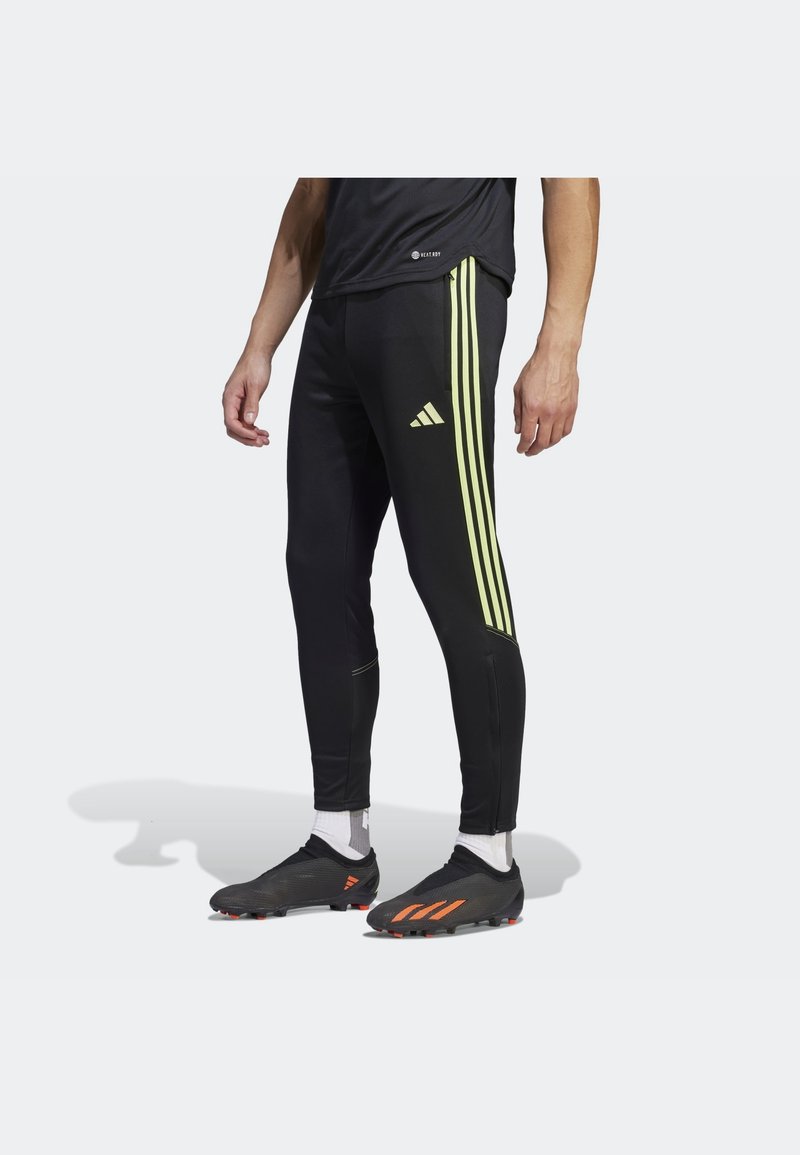 Černé sportovní legíny s třemi svislými fluorescenčními žlutými pruhy a logem. Vyrobené z pružného, lehkého materiálu s zipy u kotníků.