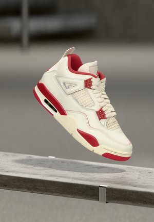 Kremowy skórzany sneaker z czerwonymi akcentami, wyposażony w panel z siateczki, wyściełany kołnierz oraz widoczną poduszkę powietrzną w podeszwie. Projekt ze sznurowaniem.