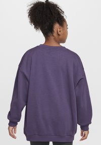 Sudadera oversized morada hecha de material suave, con un cuello y puños de canalé. Textura suave con un ajuste relajado.