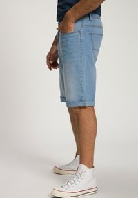 Vaaleansiniset farkkushortsit, joissa on käännetyt helmat, sivutaskut ja slim fit -malli. Yhdistetty valkoisiin korkeisiin tennareihin.