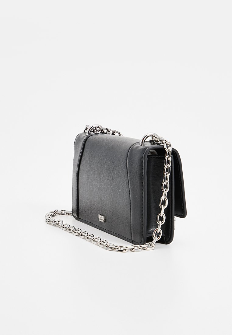 Sac en cuir noir à bandoulière avec une chaîne, de forme rectangulaire, texture lisse et design pliable. Présente un accent de logo à l'avant.