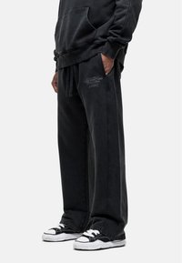 Zwarte katoen sweatpants met een relaxte pasvorm, voorzien van zijzakken en een trekkoord in de taille. Subtiele logodetails op de dij.