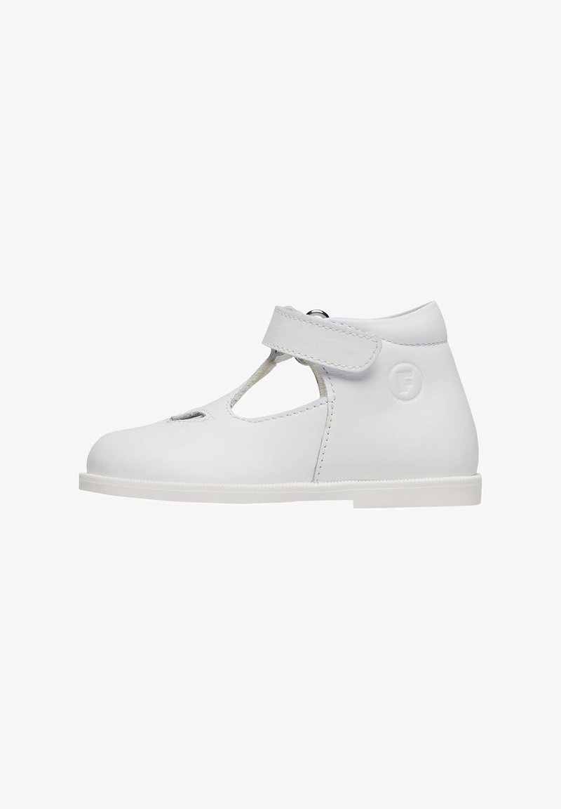 Chaussure Mary Jane en cuir blanc avec un bout rond, une bride à la cheville, des découpes et une semelle en caoutchouc plate. Texture lisse avec des accents de design simples.