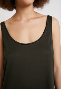 Top senza maniche verde scuro con ampio scollo rotondo e tessuto morbido e liscio. La silhouette è rilassata e leggermente aderente.