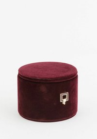 Rund bordeaux fløjlæske med en glat tekstur, med en guldfarvet firkantet låsedetalje på siden. Lukket design, blød finish.