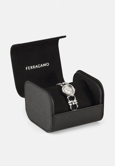 Silver Ferragamo klocka med rund urtavla, länkarmband, presenterad i en svart strukturerad låda med mjukt inre och präglad logotyp.