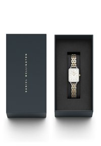 Reloj rectangular Daniel Wellington con un dial blanco, acentos dorados y una pulsera de metal bicolor, presentado en una caja azul oscura.
