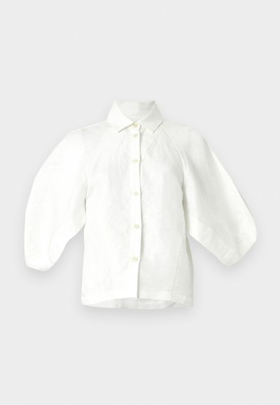 Λευκό λινό πουκάμισο με γιακά, κλείσιμο με κουμπιά μπροστά και φαρδιές, φουσκωτές μανίκες. Ομαλή υφή με άνετη σχεδίαση εφαρμογής.