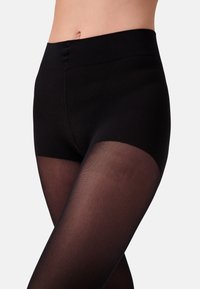 Leggings neri con vita alta, caratterizzati da una parte superiore opaca e liscia e gambe trasparenti e testurizzate, che enfatizzano un aspetto elegante e fluido.