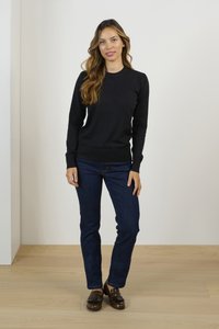 Maglione nero a maniche lunghe con polsini a coste, abbinato a jeans blu scuro e mocassini marroni. Design semplice, texture liscia.