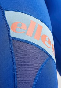 Niebieska tkanina sportowa z siateczkowym panelem, z pomarańczowymi detalami logo i jasnoniebieską sekcją akcentującą. Obecne są teksturowane i gładkie obszary.