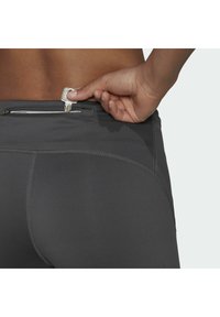 Leggings atletici grigi con cuciture piatte e una tasca con zip sicura sul retro per gli essenziali, visti di lato.