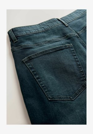 Denim jeans in dark blue, with a smooth texture. Features two back pockets with visible stitching and a waistband without embellishments.