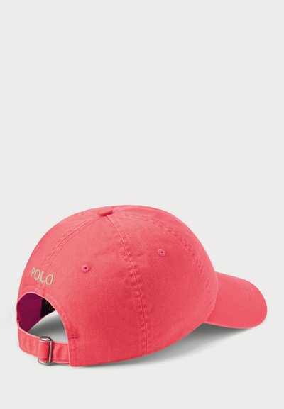 Rózsaszín pamut baseballsapka, hátul állítható pánttal és kontrasztos színű "POLO" hímzéssel. Sima tekstúra, lekerekített forma.