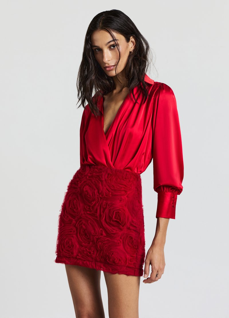 Abito rosso con un top in satin dal profondo scollo a V e maniche a sbuffo, che si trasforma in un tessuto floreale testurizzato nella gonna.