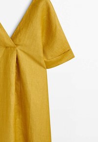 Robe jaune moutarde à manches courtes avec un profond décolleté en V et un pli devant en tissu léger texturé.