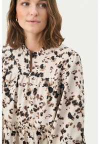 Long-sleeve dress in a lightweight, textured fabric featuring a beige, brown, and black animal print, with a ruffled neckline and tiered design.