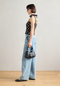 Tmavě puntíkovaný top na ramínkách se stuhami, světle modré široké džíny, černá kabelka se stříbrnými akcenty a černé baleríny.