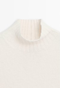 Crème turtleneck trui met een geribbelde structuur en hoge kraag. Gemaakt van zacht gebreid materiaal, met een gladde afwerking en minimale naden.