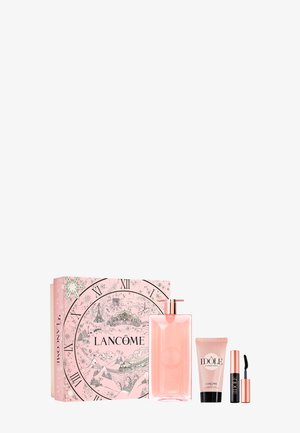 Coffret de parfum comprenant une bouteille en verre rose, des accents en or rose, un tube de crème rose et un mascara noir, le tout dans une boîte décorative rose.