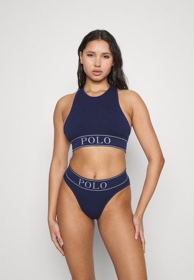 Jūras spēku ribota sporta krūšturis un bikini komplekts ar platumu joslu, uz kuras ir "POLO" logo. Dizainā ir augsta kakla forma un uzkrītošs griezums.