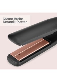 Sort hårrettetang med 36 mm brede rosegull keramiske plater vist delvis åpen på en beige bakgrunn.