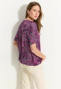 Paars blouse met korte mouwen, voorzien van een abstract patroon in wit en roze, met een ronde halslijn en een losse pasvorm, gemaakt van lichtgewicht stof.