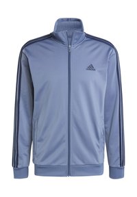 Blå atletisk jakke lavet af glat stof, med en høj krave, fuld lynlås og tre mørke striber ned ad ærmerne. Adidas-logo på brystet.