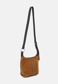 Ruskea mokkanahkainen olkaväri mustalla nahkahihnalla. Ominaisuuksiin kuuluu yksinkertainen muoto, näkyvä sauma keskellä ja hopeiset metalliosat.