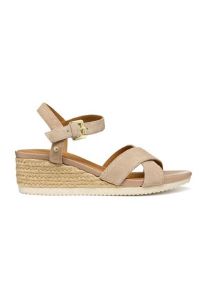 Beige ruskind kile-sandal med ankelrem, gylden spænde, flettet jute platform og åben tå på hvid baggrund.