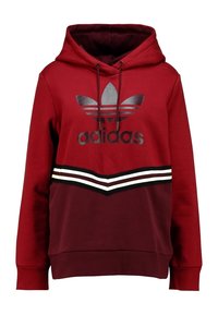 Röd luvtröja med en svart Adidas-logga på framsidan, utrustad med horisontella ränder i vitt och svart vid midjan. Mjuk textur.