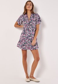 Blumenkleid mit kurzen Ärmeln, gerafftem Ausschnitt und taillierter Passform. Verziert mit rosa, weißen und grünen Mustern auf einem dunkelblauen Hintergrund.