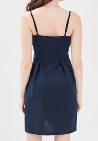 Vestido azul marino con tirantes finos, corsé ajustado y falda con plisados. Textura suave con un diseño simple y elegante y una silueta entallada.