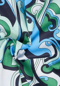 Tissu à motifs avec des formes tourbillonnantes en vert, bleu et noir sur fond blanc. Le matériau semble lisse avec une finition brillante.