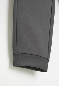 Szary mankiet od bluzy z ribbowanym wzorem, w jednolitym kolorze, z czystym detalem szwu wzdłuż szwu. Miękki, elastyczny materiał.