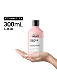 Rosa plastflaske med L'Oréal sjampo holdt i en hånd, med svart hette og hvit etikett med produktdetaljer og volum på 300 mL.