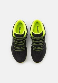 Czarne buty sportowe z teksturowanym wzorem, akcentami w jasnozielonym kolorze i odblaskowymi sznurowadłami. Posiadają wyściełany kołnierz oraz logo na wkładce.