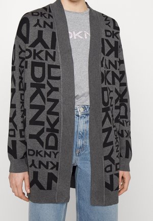 Cardigan gris ouvert à l'avant avec motif logo noir DKNY, porté sur un t-shirt gris DKNY et un jean en denim bleu clair.