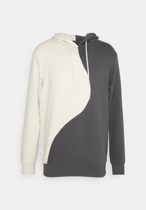 Bluza z kapturem z pół na pół białym i ciemnoszarym wzorem yin-yang, długimi rękawami, sznurkami oraz ściągaczami na mankietach i dole.