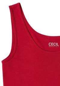 Débardeur rouge sans manches, à encolure ronde, coutures apparentes et étiquette blanche « "Cecil Essentials" » près du col. Aucun fond visible.