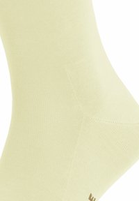 Jasnożółta skarpetka typu crew, wykonana z materiału rypsowego, charakteryzująca się gładką teksturą i subtelnym detalem logo blisko mankietu.