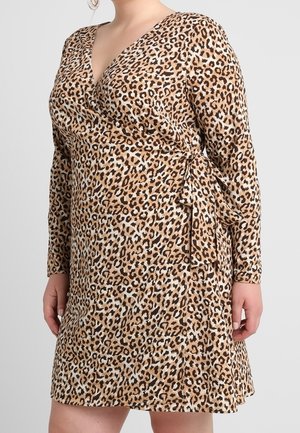 Vrouw die een wikkeljurk met lange mouwen en luipaardprint draagt, geknoopt in de taille met een V-hals.
