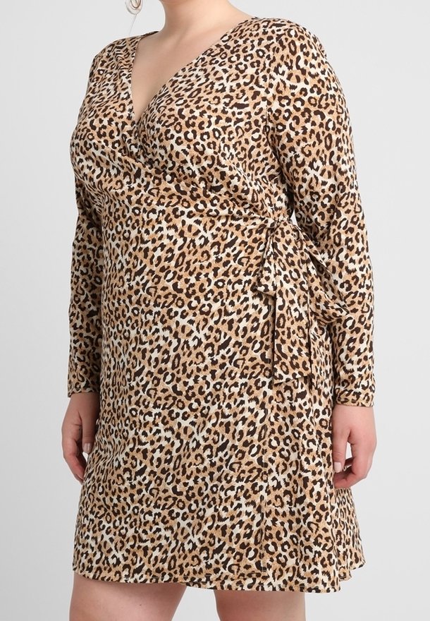 Femme portant une robe portefeuille à manches longues imprimée léopard, nouée à la taille avec un décolleté en V.