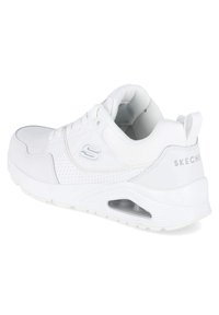 Baskets Skechers blanches avec une tige texturée, des détails perforés, un design à lacets, un col rembourré et une unité de coussin d'air visible.