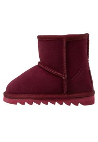 Botín de ante burdeos con puntera redonda, suela plana y acentos cosidos. Presenta un forro interior suave y una suela exterior con patrón de zigzag.