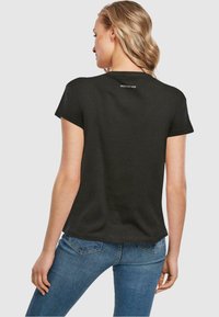 Sort bomulds T-shirt med korte ærmer; har en rund halsudskæring og et lille hvidt logo på ryggen. Par med blå jeans.